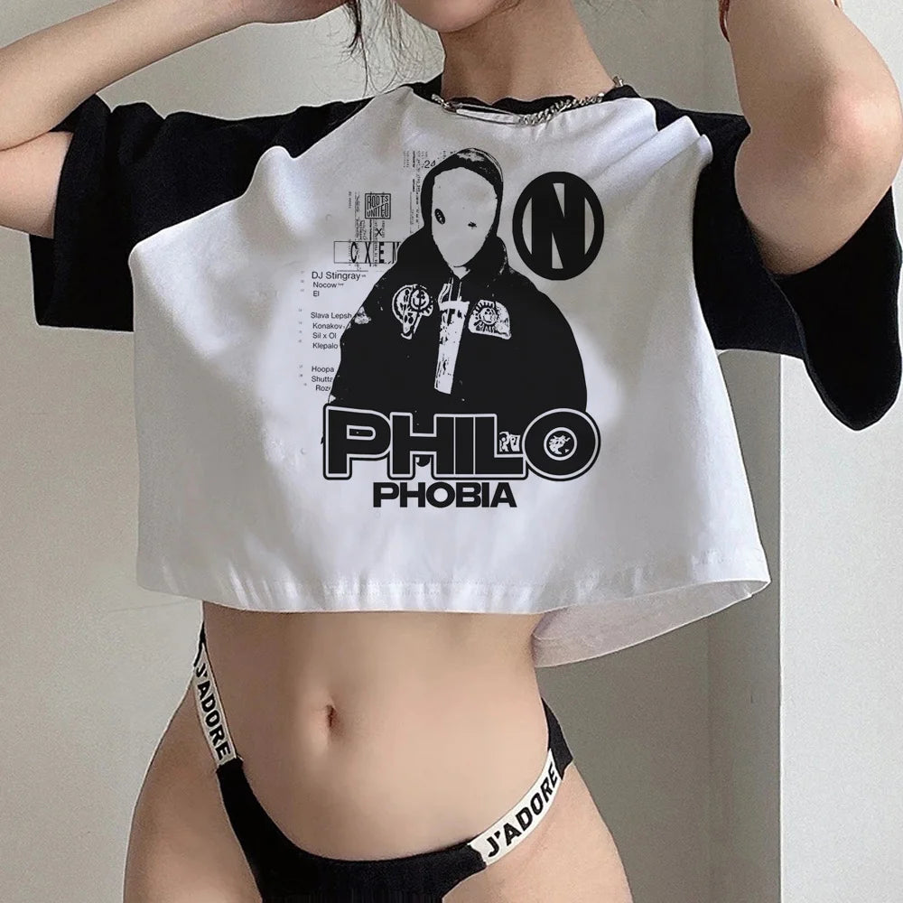 Person wearing a white crop top with black sleeves and graphic design, paired with black underwear.